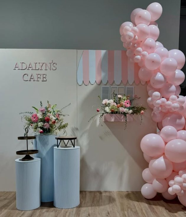 Pink organic balloon garland on a custom cafe backdrop with pedestals and florals