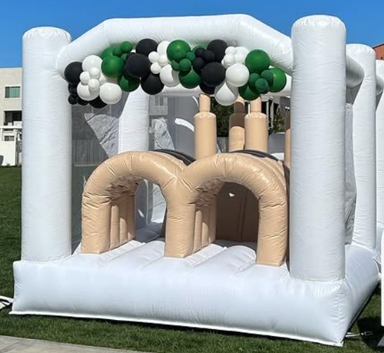 White inflatable obstacle course with dual arch lanes and a green balloon garland