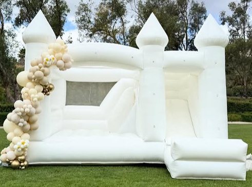 White castle combo bounce house with slide and a neutral balloon garland in an Irvine backyard